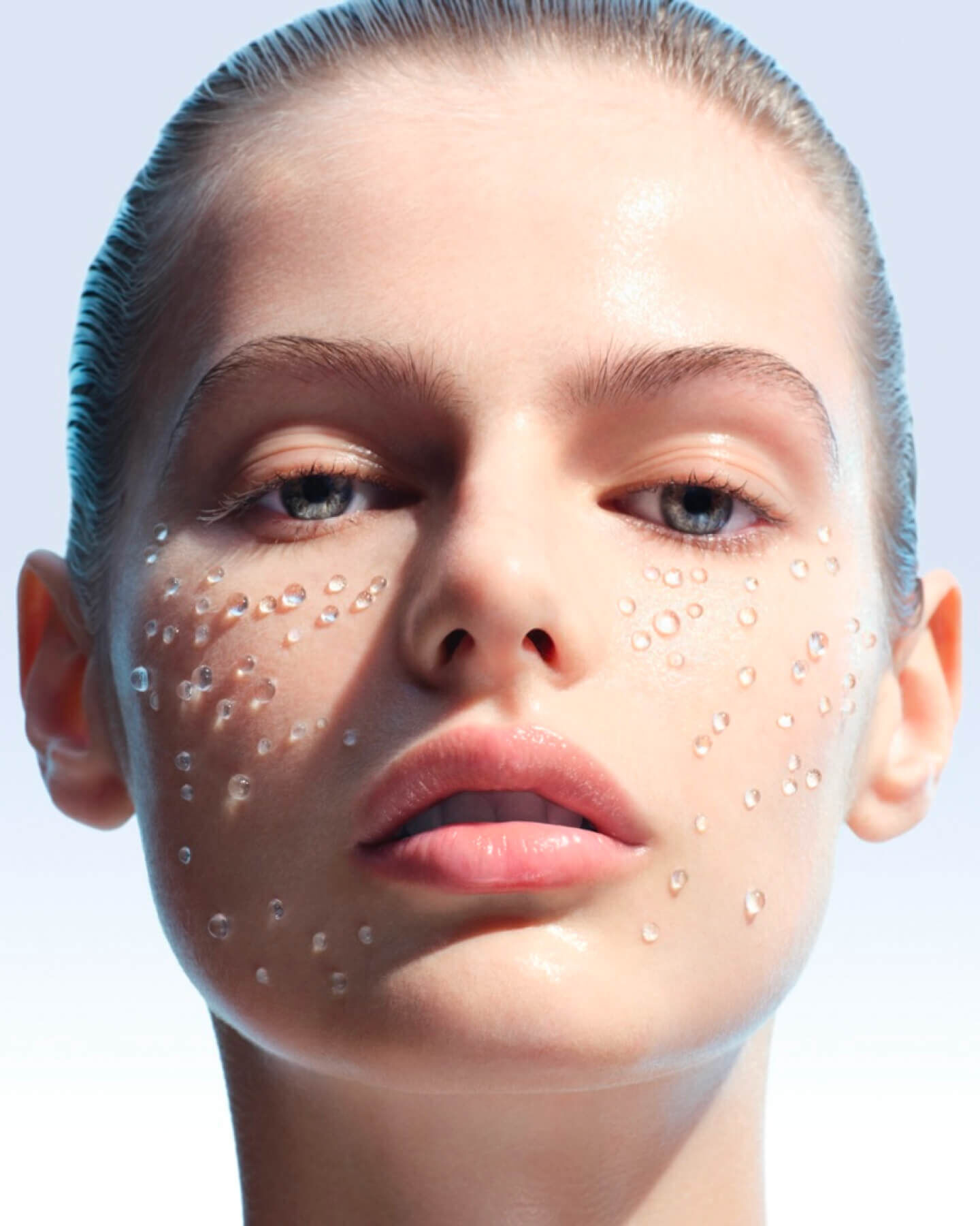 Close-up of a woman’s face with visible water droplets on the skin, illustrating hydration.