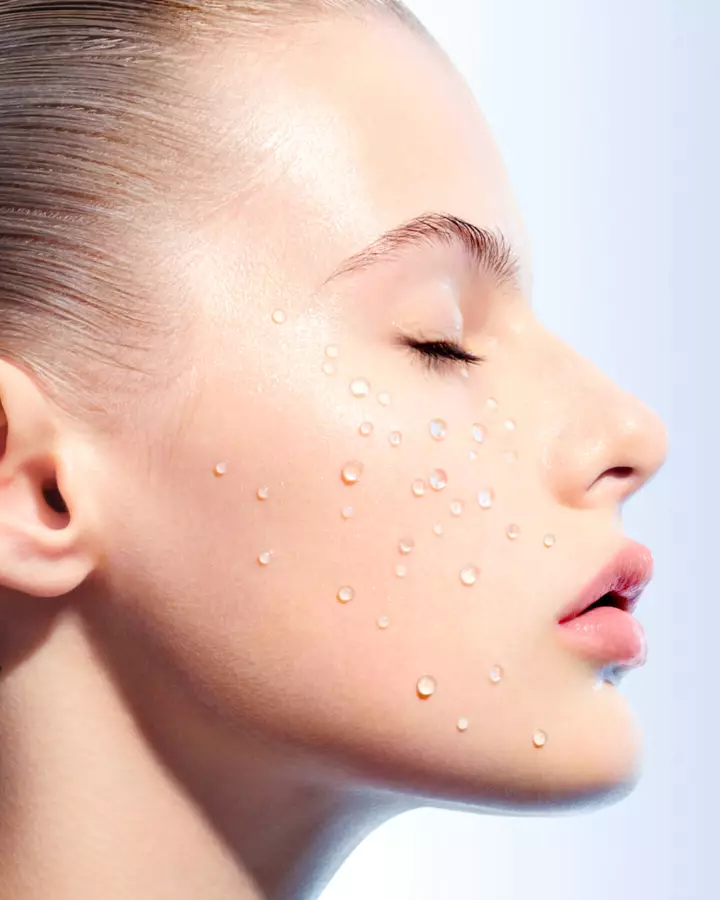 Close-up profile of a woman’s face with water droplets on her skin.